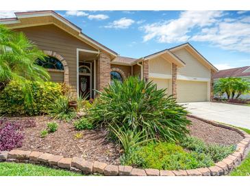 Beautifully landscaped front yard with lush plantings and brick-edged garden beds create inviting curb appeal at 11209 Bloomington Dr, Tampa, FL 33635