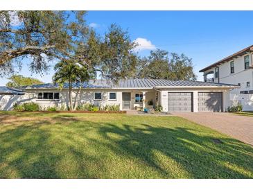 Charming single-story home with a well-manicured lawn, a gray roof and a two car garage at 3961 12Th Ne St, St Petersburg, FL 33703