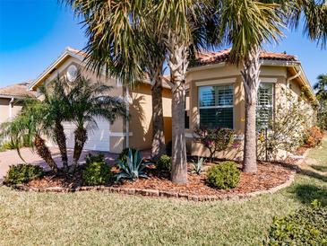 Charming single-story home featuring a barrel tile roof, lush tropical landscaping, and an attached two-car garage at 4822 Grand Banks Dr, Wimauma, FL 33598