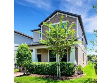 Charming two-story home with well-manicured lawn, mature trees, and inviting covered front porch at 3568 Pine Ribbon Dr, Land O Lakes, FL 34638