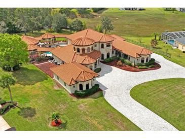 Expansive estate featuring terracotta roofing, a circular driveway, and lush green landscaping at 11158 Warm Wind Way, Weeki Wachee, FL 34613