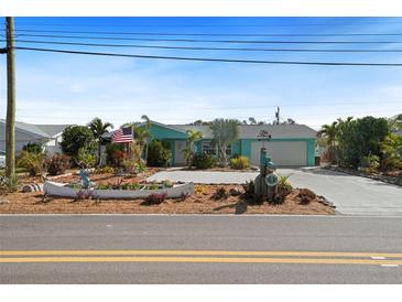 Charming one-story home with a well-manicured lawn, colorful decorations, and a long driveway at 9911 Antilles Dr, Seminole, FL 33776