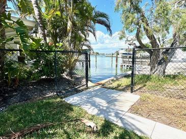 Waterfront view through a gated fence showing a private dock, and beautiful foliage on a sunny day at 619 59Th Ave, St Pete Beach, FL 33706