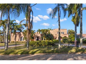 Beautiful home exterior showcasing lush landscaping, a brick street, mature palm trees, and wrought iron fencing at 6935 Date Palm S Ave, St Petersburg, FL 33707