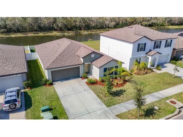 Well-maintained single-story home featuring a two-car garage, landscaping, and a view of the water at 7132 Samuel Ivy Dr, Tampa, FL 33619