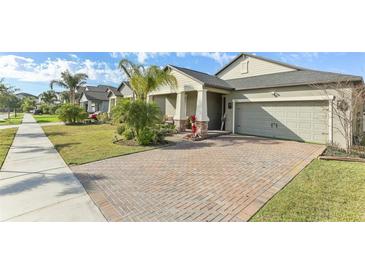 Charming single-Gathering home showcasing a brick-paved driveway and lush front lawn at 13218 Satin Lily Dr, Riverview, FL 33579
