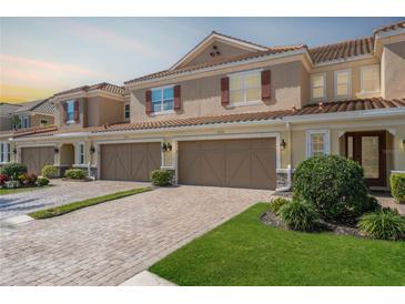 Charming townhome showcasing a well-manicured lawn and paver driveway leading to a two-car garage at 12326 Terracina Chase Ct, Tampa, FL 33625