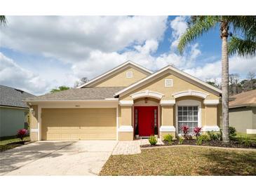 Inviting single-story home boasts a well-manicured lawn, red front door, and an attached two-car garage at 5913 Lawrin Ct, Wesley Chapel, FL 33544