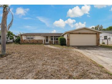 Single-story home with stone accents, attached garage and a large front yard on a sunny day at 6636 Carnation Way, Port Richey, FL 34668