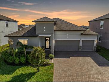 Beautiful single-Gathering home showcasing a three-car garage, brick driveway, and meticulously landscaped front yard at 11717 Navajo Sandstone St, Riverview, FL 33579