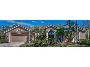 Beautiful home featuring lush landscaping, a barrel tile roof, and a two-car garage at 9101 Highland Ridge Way, Tampa, FL 33647