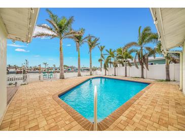 Inviting in-ground pool with brick surround and towering palm trees in this waterfront backyard at 7984 1St S Ave, St Petersburg, FL 33707