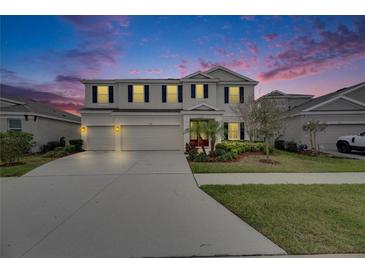 Elegant two-story home boasts a three-car garage and well-manicured landscaping at twilight at 7528 Paradiso Dr, Apollo Beach, FL 33572