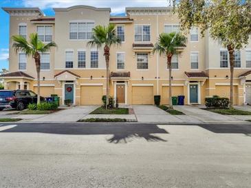 View of a three-story townhouse with a tan exterior, complemented by palm trees and individual garages at 3106 Bayshore Oaks Dr, Tampa, FL 33611