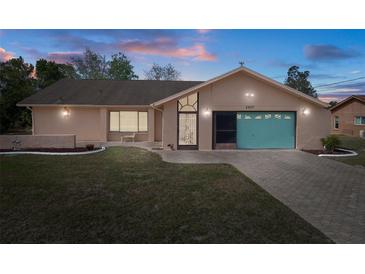 Charming single-story home with a well-maintained lawn, colorful garage door, and welcoming curb appeal at 5357 Kirkwood Ave, Spring Hill, FL 34608