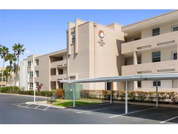 A view of the condo building with covered parking and landscaping at 7425 Bay Island S Dr # 202, South Pasadena, FL 33707