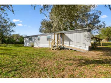 Charming single-story home with gray siding, wooden ramp and stairs, with a large grassy front yard at 8408 Bob Wiggs Ave, Lithia, FL 33547