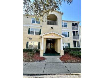 Inviting condominium complex featuring three floors, yellow siding, green shutters, well-maintained landscaping and walkway at 18121 Bridle Club Dr # 18121, Tampa, FL 33647