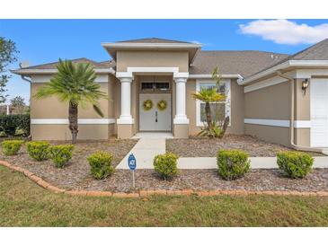 Charming home featuring a covered front entrance with columns and a well-manicured lawn with palm trees at 2250 Long View Cir, Brooksville, FL 34604
