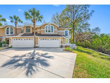 Inviting townhouse showcasing a two-car garage and tropical palm trees accenting the property at 3042 Branch Dr, Clearwater, FL 33760