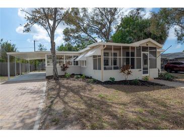 Quaint home with a screened porch and carport, complemented by a brick driveway and lush landscaping at 560 80Th N Ave, St Petersburg, FL 33702