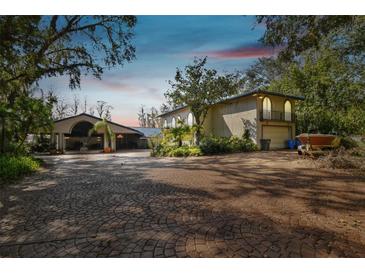 Exterior of home featuring a unique driveway, covered entry, and mature landscaping at 8510 Lays Cove Pl, Odessa, FL 33556