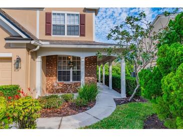 Charming covered front porch with brick accents, perfect for relaxing outdoors, with lush landscaping around walkway at 4654 Pond Ridge Dr, Riverview, FL 33578