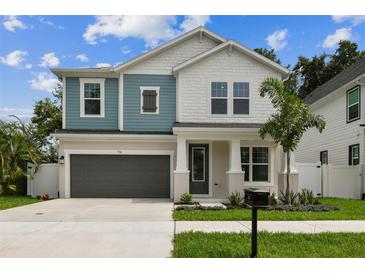 Charming two-story home featuring blue and white accents, a gray garage door, and a well-manicured front yard at 713 W West St, Tampa, FL 33603