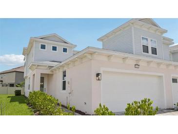 Charming two-story home featuring light exteriors, a large garage, and lush green landscaping at 31857 Anchor Point Dr, Wesley Chapel, FL 33545