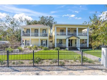 Charming, bright yellow two-story home featuring dual balconies and a well-manicured front lawn at 732 Oak Ne St, St Petersburg, FL 33701