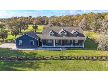 Charming blue home featuring a welcoming front porch, well-manicured lawn, and a classic fence enhancing its curb appeal at 10946 Gun Dog Way, Lithia, FL 33547
