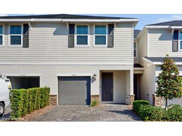 Charming two-story townhouse with gray garage door, stone accents, and manicured landscaping at 15033 Abby Birch Pl, Tampa, FL 33613