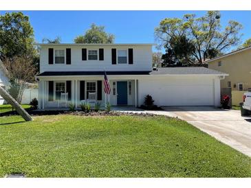 Charming two-story home with well-manicured lawn, blue door, and front porch with rocking chairs at 4912 W Dryad St, Tampa, FL 33629