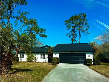 Charming single-story home featuring a two-car garage, a driveway, and a well-maintained lawn with mature trees at 5144 Pine Tree Ln, Wesley Chapel, FL 33543