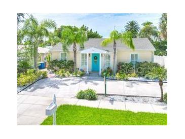 Charming home featuring a bright blue front door and lush tropical landscaping at 744 Bay Esplanade, Clearwater Beach, FL 33767