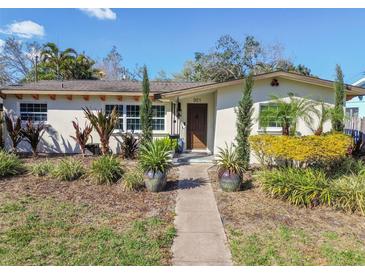 Charming home featuring meticulously landscaped front yard with mature trees and vibrant flower beds at 921 39Th Ne Ave, St Petersburg, FL 33703