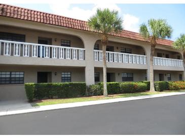 Two-story condo featuring a red tile roof, second story balconies, and manicured landscaping at 1750 Belleair Forest Dr # A7, Belleair, FL 33756