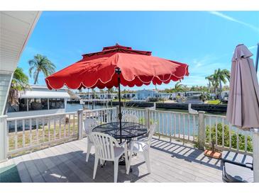 Waterfront deck view with an umbrella, table, chairs, and railing overlooking the tranquil canal at 18675 Us Highway 19 N # 251, Clearwater, FL 33764