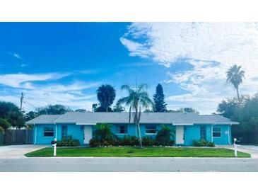 Inviting blue exterior of this charming duplex with a well manicured lawn and lovely tropical landscaping at 2011 1St St, Indian Rocks Beach, FL 33785