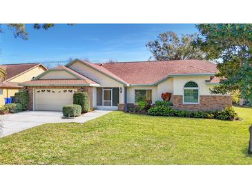 Charming single-story home with well-manicured lawn, brick accents, and a two-car garage at 2725 Onizuka Ct, Palm Harbor, FL 34683