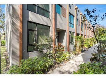 Modern townhome featuring a stylish facade with large windows and lush landscaping at 4156 Gauge Line Loop, Tampa, FL 33624