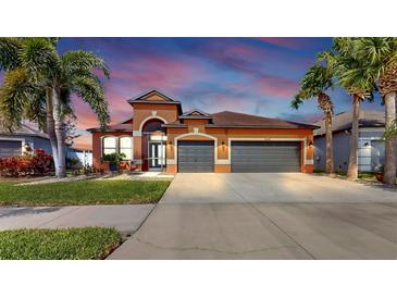 Charming orange home with a three-car garage, well-maintained lawn, and attractive landscaping in a sunny locale at 8436 White Poplar Dr, Riverview, FL 33578