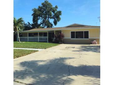 Charming single-story home featuring a well-manicured lawn and a welcoming covered porch with white picket fence at 1149 6Th Ne Ave, Largo, FL 33770
