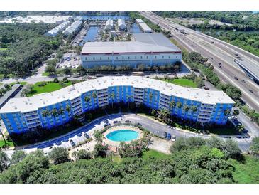 Stunning aerial view of a modern, bright blue condo building with a community pool surrounded by lush trees and landscaping at 3315 58Th S Ave # 314, St Petersburg, FL 33712
