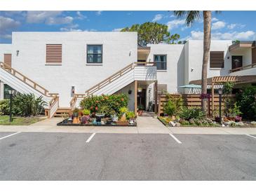 Bright condo complex featuring white stucco, wood trim, colorful landscaping, and convenient parking at 127 Tidewater Dr # 127, Bradenton, FL 34210