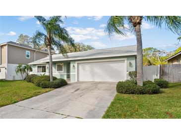 Inviting one-story home with two-car garage, mature landscaping, and a well-maintained lawn at 45 Gulfwinds W Dr, Palm Harbor, FL 34683