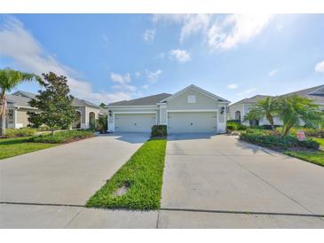 Charming home exterior featuring a spacious two-car garage and well-manicured landscaping with green grass and a blue sky at 4524 Deep Creek Ter, Parrish, FL 34219