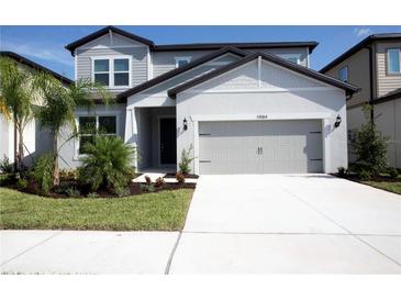 Charming two-story home with a manicured lawn and a spacious driveway leading to a two-car garage at 14184 Hammock Crest Way, Riverview, FL 33569