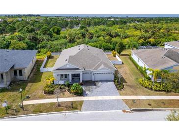 Beautiful aerial view of single-story home with lush landscaping and gray brick driveway at 618 Manns Harbor Dr, Apollo Beach, FL 33572