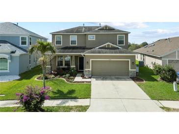 Two-story home featuring an attached garage, manicured lawn, and a beautiful landscape at 11517 Weston Course Loop, Riverview, FL 33579